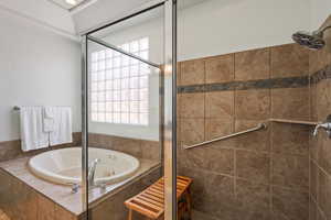 Bathroom with a shower stall and a tub with jets