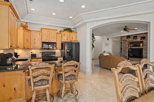 Kitchen featuring black appliances, arched walkways, a ceiling fan, recessed lighting, and a peninsula