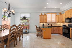 Kitchen with black appliances, healthy amount of natural light, a chandelier, a kitchen breakfast bar, and recessed lighting
