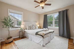 Bedroom featuring multiple windows, baseboards, light wood-type flooring, and ceiling fan