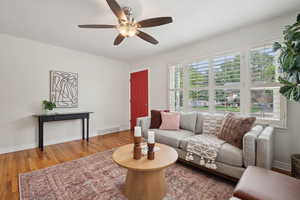 Living area featuring a ceiling fan, wood finished floors, and baseboards