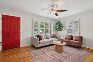 Living room with ceiling fan, light wood-type flooring, and baseboards