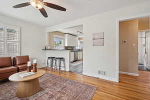 Living room featuring light wood-style flooring, track lighting, a ceiling fan, and baseboards