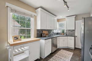 Kitchen with stainless steel appliances, a sink, healthy amount of natural light, and white cabinetry