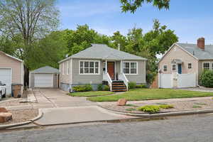 Bungalow-style house with an outbuilding, a garage, a gate, driveway, and a shingled roof