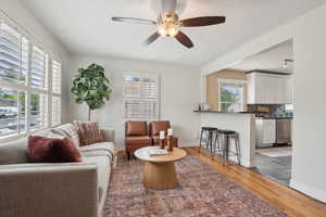 Living room with a ceiling fan, wood finished floors, and baseboards