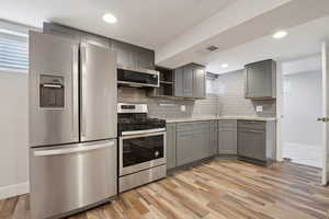 Kitchen with stainless steel appliances, gray cabinetry, baseboards, decorative backsplash, and recessed lighting