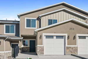 View of front of property featuring stone siding, board and batten siding, stucco siding, and concrete driveway