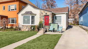 View of front facade featuring stone siding, a front yard, and a shingled roof