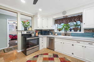Kitchen with appliances with stainless steel finishes, a ceiling fan, a sink, light countertops, and crown molding