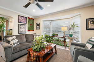 Living room with a ceiling fan, crown molding, arched walkways, and recessed lighting