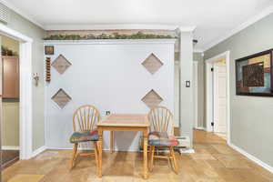 Dining room featuring stone tile floors, crown molding, and baseboards