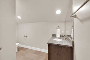 Bathroom featuring vanity, toilet, and baseboards