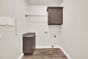 Washroom featuring electric dryer hookup, dark wood-type flooring, hookup for a washing machine, baseboards, and cabinet space