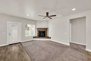 Unfurnished living room with baseboards, recessed lighting, ceiling fan, a glass covered fireplace, and wood finished floors