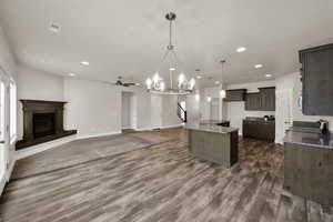 Kitchen with a sink, light stone counters, dark wood finished floors, recessed lighting, and dark brown cabinetry