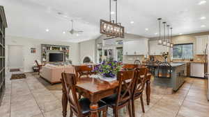 Dining room featuring ceiling fan, light tile patterned floors, lofted ceiling, recessed lighting, and a chandelier
