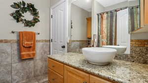 Full bath featuring tile walls, vanity, a wainscoted wall, and a shower with shower curtain