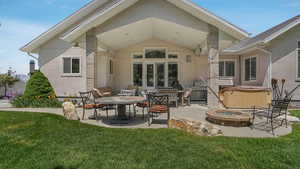 Rear view of property with a hot tub, a patio, and stucco siding