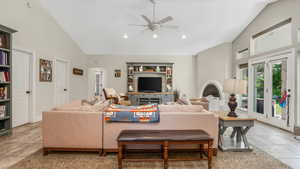 Living area featuring a ceiling fan, high vaulted ceiling, light tile patterned floors, and recessed lighting
