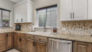 Kitchen featuring stainless steel dishwasher, a sink, and tasteful backsplash