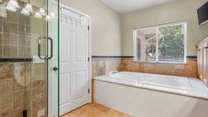 Bathroom featuring a garden tub, a shower stall, and a wainscoted wall