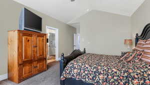 Carpeted bedroom with lofted ceiling and ensuite bathroom
