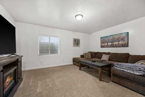 Living room featuring a glass covered fireplace, carpet floors, and baseboards