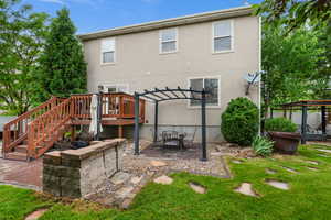 Back of property with a pergola, a deck, a yard, a patio area, and stucco siding
