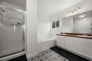 Primary - Full bathroom featuring a stall shower, a bath, double vanity, and tile patterned flooring