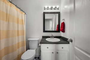 Bathroom with toilet, vanity, and a shower with shower curtain