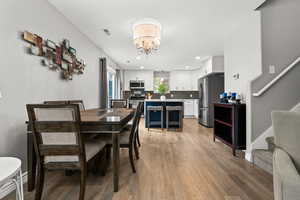 Dining area featuring a chandelier, stairs, light wood-style floors, recessed lighting, and baseboards