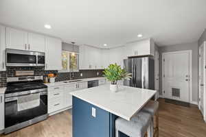 Kitchen featuring stainless steel appliances, a sink, backsplash, white cabinets, and recessed lighting