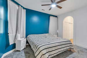 Bedroom featuring carpet, baseboards, arched walkways, and ceiling fan