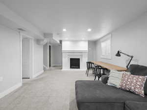 Living area with carpet floors, baseboards, a fireplace, and recessed lighting