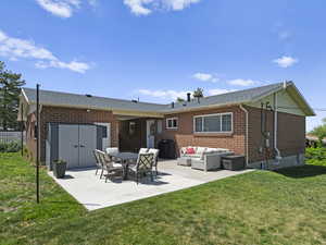 Back of property with outdoor lounge area, brick siding, a patio area, and a yard