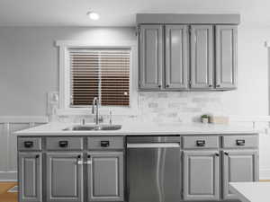 Kitchen featuring dishwasher, gray cabinetry, a sink, and light countertops