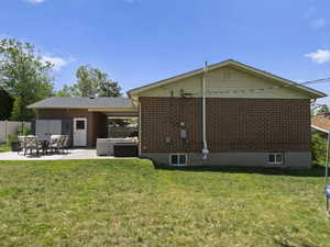 Back of property featuring a patio, brick siding, and a jacuzzi