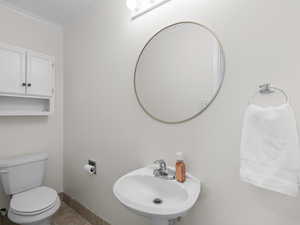 Bathroom with a sink, ornamental molding, toilet, baseboards, and tile patterned flooring