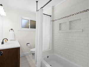Bathroom featuring tile patterned flooring, shower / tub combo with curtain, toilet, vanity, and baseboards