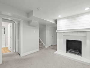 Unfurnished living room featuring carpet floors, stairway, baseboards, a fireplace, and recessed lighting