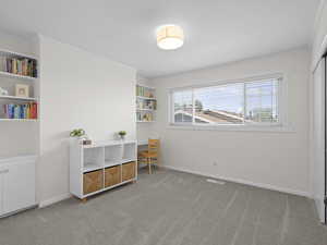 Sitting room featuring carpet, crown molding, baseboards, and built in shelves
