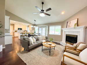 Living area featuring lofted ceiling, ceiling fan, wood finished floors, a fireplace, and baseboards