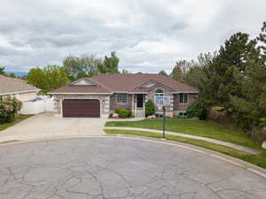 Single story home featuring driveway, an attached garage, and brick siding