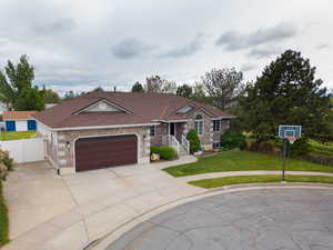 Ranch-style home featuring brick siding, an attached garage, a gate, a shingled roof, and concrete driveway