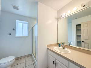 Full bathroom featuring toilet, a stall shower, vanity, and tile patterned flooring