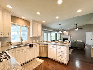 Kitchen with stainless steel dishwasher, a sink, a peninsula, plenty of natural light, and vaulted ceiling