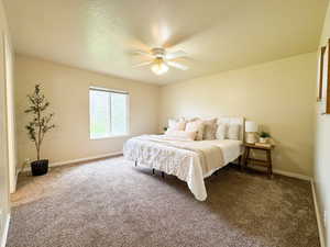 Bedroom with carpet flooring, baseboards, a ceiling fan, and a textured ceiling
