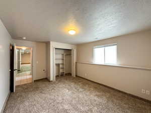 Unfurnished bedroom with a closet, light carpet, a textured ceiling, and baseboards