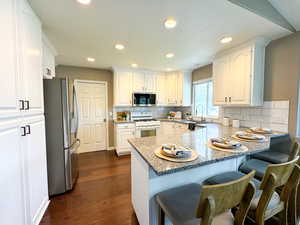 Kitchen featuring stainless steel appliances, a peninsula, a sink, white cabinets, and a kitchen breakfast bar